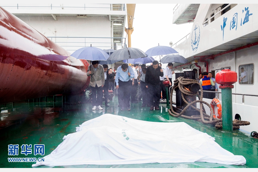 这是在码头边的趸船上，救援人员刚刚搜救出几具遇难乘客的遗体。李克强及随行人员向逝者鞠躬默哀，表达对逝者的尊重。 新华社记者 黄敬文 摄