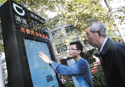 10月15日，滴滴工作人员（左）指导乘客使用&ldquo;滴滴车站&rdquo;的电子屏预约出租车。10月14日起，上海首批&ldquo;滴滴车站&rdquo;上线启用。新华社记者 裴鑫 摄