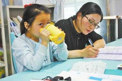 杨崇利老师在备课,孩子在身旁等待。