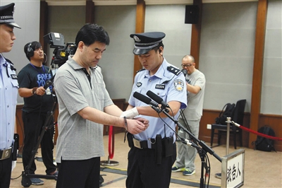 昨日法院宣判后,北京"红通"首名归案者孙新被法警戴上手铐.