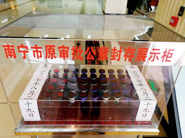 在南宁市民中心大厅的展示柜内,40 个有关部门的原审批公章被封存今年
