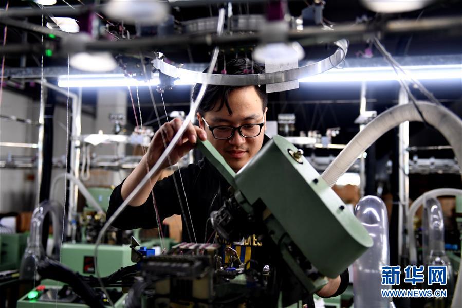 5月2日,钟文在东北袜业园的袜厂检查织袜机.